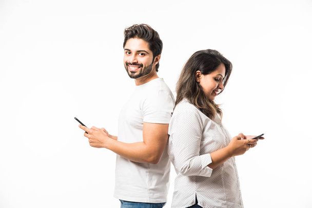 Indiase paar met behulp van smartphone/mobiele handset, staande geïsoleerd over witte achtergrond - Foto, afbeelding