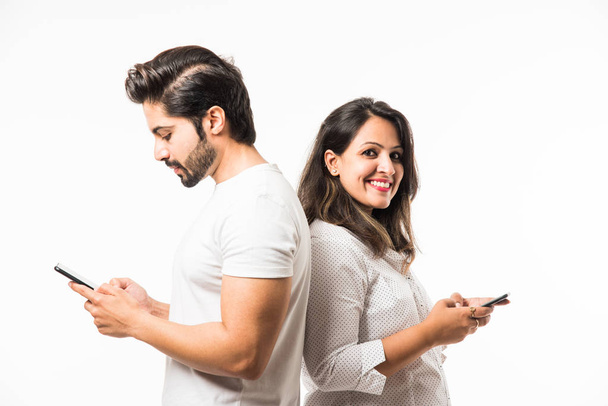 Akıllı telefon / cep telefonu kullanarak Hint çift, beyaz arka plan üzerinde izole ayakta - Fotoğraf, Görsel