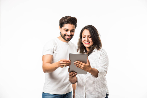 白い背景の上に孤立した立ちながらタブレットコンピュータを使用してインドのカップル - 写真・画像