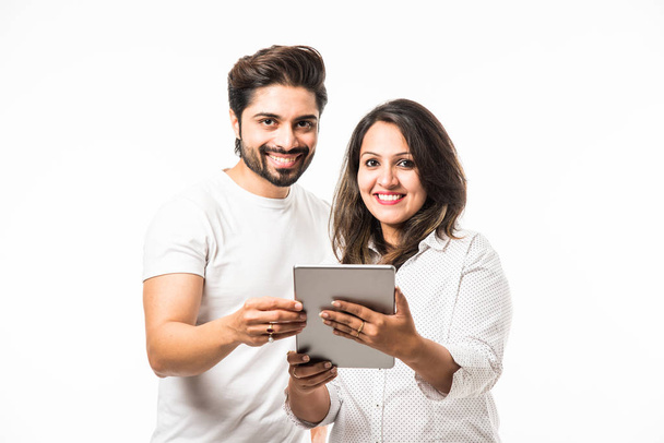 Indian couple using tablet computer while standing isolated over white background - Photo, image
