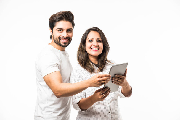 Indian couple using tablet computer while standing isolated over white background - 写真・画像