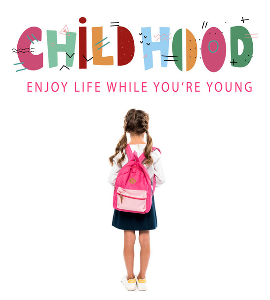back view of schoolchild standing with pink backpack near childhood lettering on white  - Photo, image