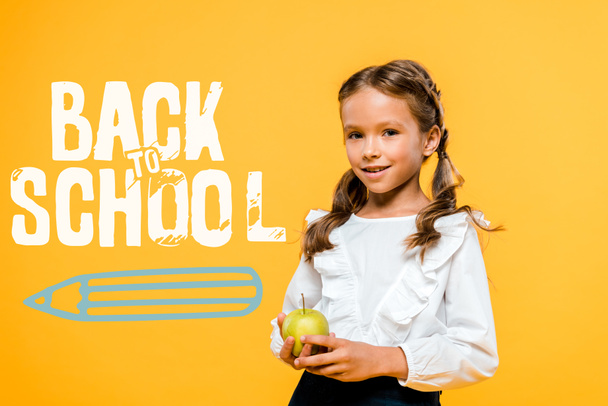estudante feliz segurando maçã saborosa perto de volta à escola lettering em laranja
  - Foto, Imagem