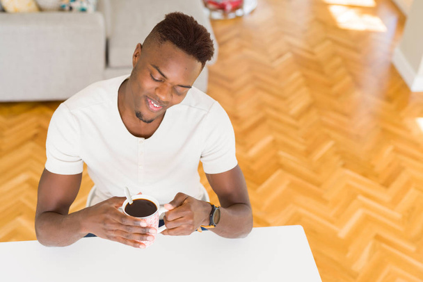 African american man smiling confident drinking a coffee at home - Photo, Image
