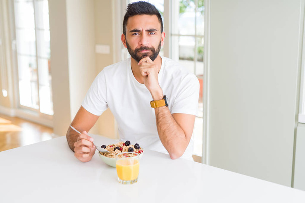 Pohledný Hispánec pojídá zdravou snídani ráno doma seriózní tvář přemýšlící o otázce, velmi zmatené myšlence - Fotografie, Obrázek