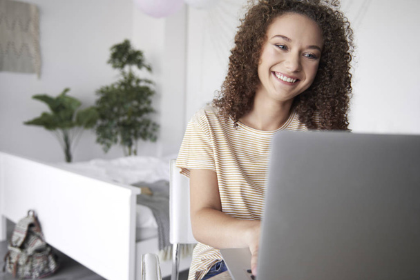 Uśmiechnięta Nastoletnia dziewczyna za pomocą laptopa w swoim pokoju  - Zdjęcie, obraz