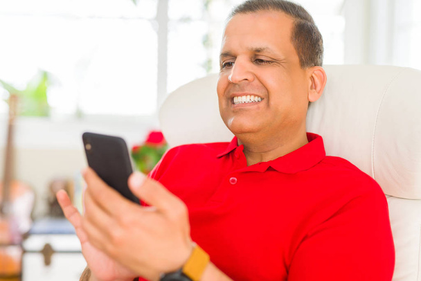 Middle age man smiling cheerful white using smartphone sitting on the sofa at home - Photo, image
