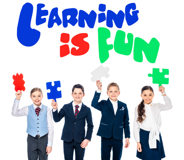 happy kids in formal wear holding puzzle pieces near learning is fun lettering on white - Foto, imagen
