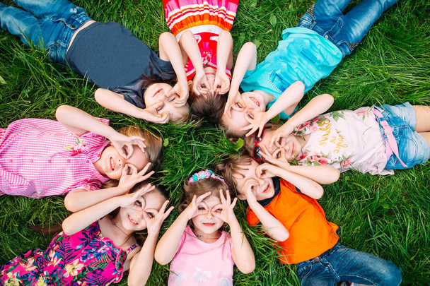A group of children lying on the green grass in the Park. The interaction of the children. - Photo, Image
