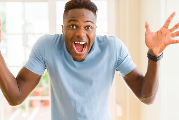 Afrikkalainen amerikkalainen mies huutaa hyvin innoissaan ja juhlii menestystä ja voittoa, hymyillen iloinen ja iloinen
 - Valokuva, kuva