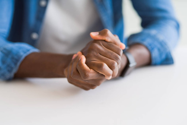 Close up of crossed hands of african man over table - Фото, изображение