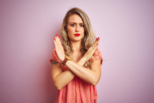 Young beautiful woman wearing t-shirt standing over pink isolated background Rejection expression crossing arms doing negative sign, angry face - Photo, Image
