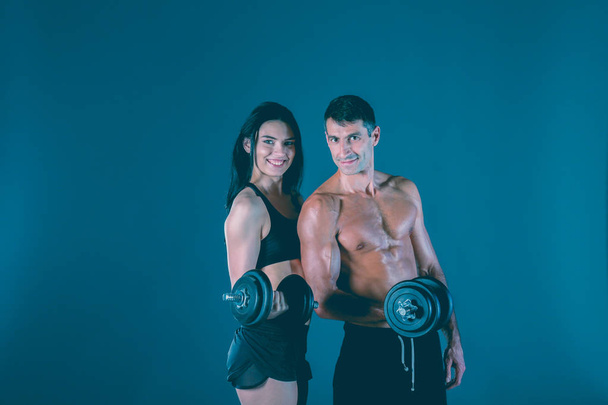 Athletic man and woman with dumb-bells. Personal fitness instructor. Personal training. Weight training. Workout. - Photo, Image