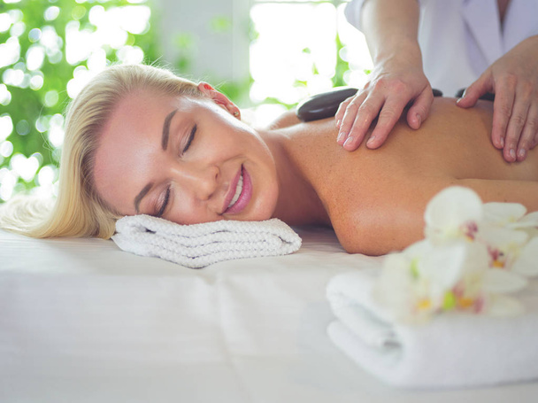 Beautiful young woman relaxing during full body massage at spa. - Фото, изображение