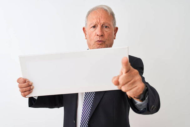 Senior businessman wearing suit holding banner over isolated white background pointing with finger to the camera and to you, hand sign, positive and confident gesture from the front - Foto, imagen