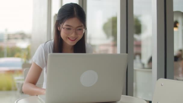 Szabadúszó ázsiai nők dolgozó laptop a kávézóban. Fiatal Ázsia üzleti lány segítségével a számítógép a kereskedelem, küldjön e-mailt, digitális munka az interneten az asztalra a szabadtéri kávézóban esti koncepció. Lassított mozgás - Felvétel, videó