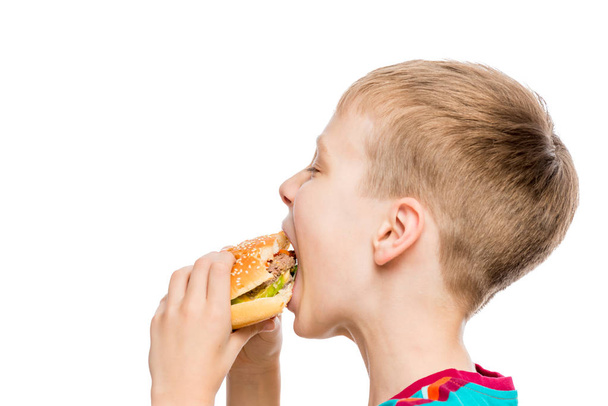 κοντινό πορτρέτο ενός πεινασμένων αγόρι με ένα χάμπουργκερ σε λευκό πίσω - Φωτογραφία, εικόνα
