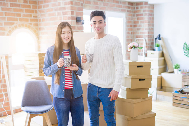 Gyönyörű fiatal ázsiai házaspár keres boldog és mosolygó izgatott költözött egy új otthont és gazdaság csészék - Fotó, kép