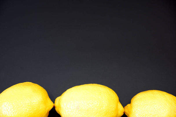 Three juicy fresh lemons on dark gray background with free space for custom text close up view - Фото, изображение