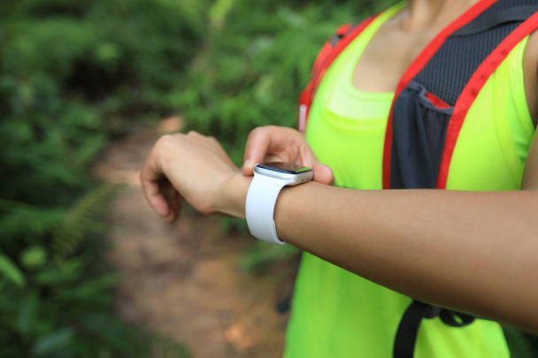 Asian woman ultramarathon runner set the sports watch before running at tropical rainforest trail - Фото, зображення