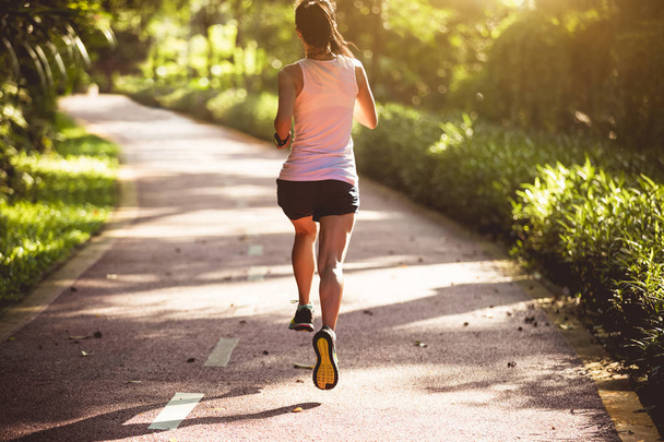 サマーパークトレイルを走る女性ランナー。健康的なフィットネス女性は屋外でジョギング.   - 写真・画像
