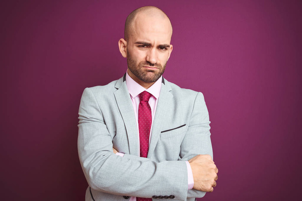 Young business man wearing suit and tie over purple isolated background skeptic and nervous, disapproving expression on face with crossed arms. Negative person. - Photo, Image