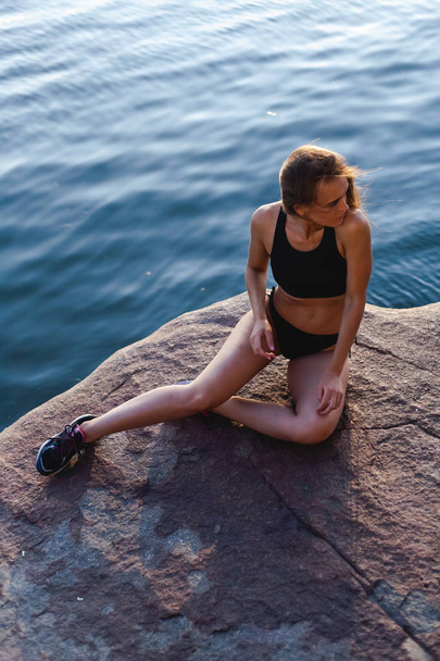 Beautiful, athletic girl in sneakers. Outdoors in a rocky area of the island. - Zdjęcie, obraz