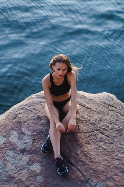 Beautiful, athletic girl in sneakers. Outdoors in a rocky area of the island. - Fotografie, Obrázek