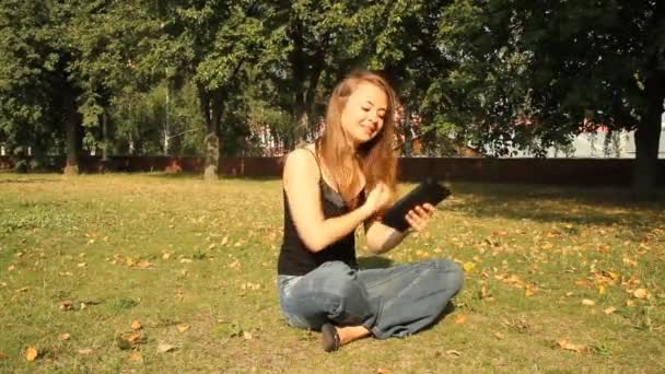 Egy fiatal lány a parkban, egy tabletta számítógép. Nyári - Felvétel, videó