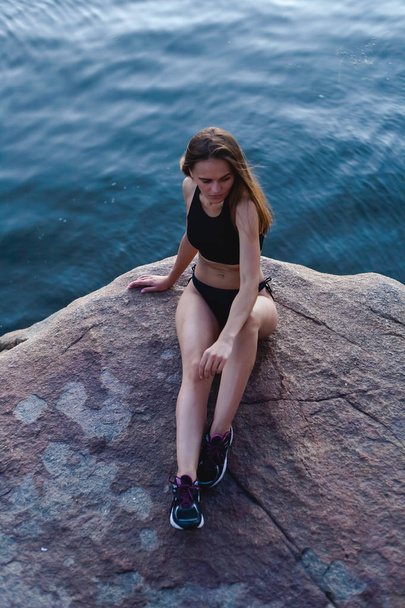 Beautiful, athletic girl in sneakers. Outdoors in a rocky area of the island. - Photo, Image