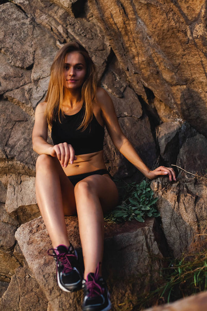 Kaunis, urheilullinen tyttö lenkkareissa. Ulkona saaren kallioisella alueella
. - Valokuva, kuva