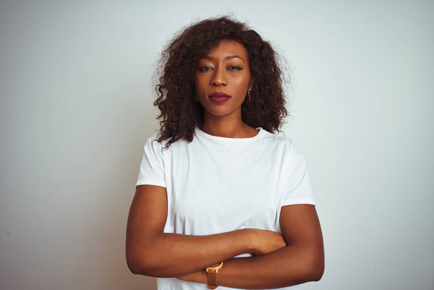 Genç afro-amerikan kadın izole beyaz arka plan üzerinde duran t-shirt giyen şüpheci ve sinirli, çapraz kolları ile yüzünde onaylamayan ifade. Negatif kişi. - Fotoğraf, Görsel