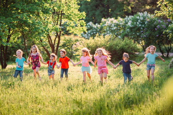 Large group of kids, friends boys and girls running in the park on sunny summer day in casual clothes . - Foto, Imagem