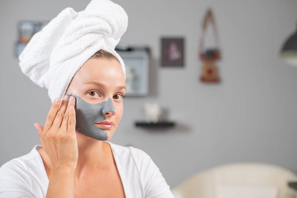 Hermosa mujer está aplicando máscara de arcilla facial. Tratamientos de belleza y cuidado de la piel
 - Foto, Imagen