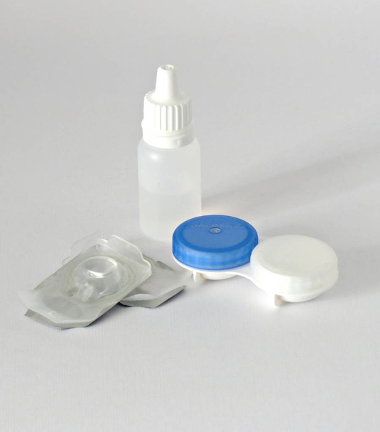 Contact lenses, case and bottle with solution on gray background. - Фото, зображення