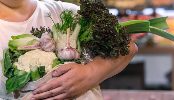 Hafta sonu çiftçi pazarında pamuk torba içinde taze olgun organik brokoli, yeşillik ve sebze ile salata tutan kadın elleri - Fotoğraf, Görsel