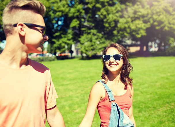 happy teenage couple walking at summer park - Foto, afbeelding
