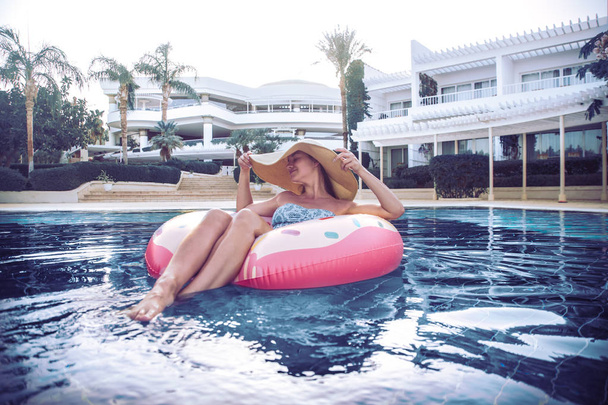 Sommerurlaub am Pool. Frau auf einem aufblasbaren Donut - Foto, Bild