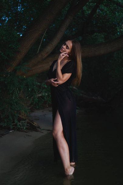 Hermosa modelo en un traje de baño negro y pareo posando en la costa
. - Foto, imagen