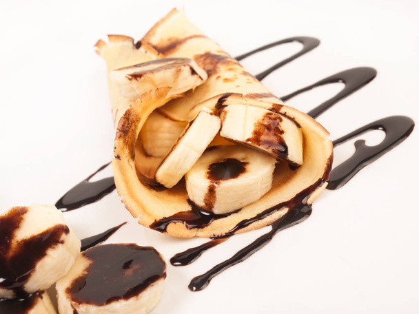 Pannenkoeken met bananen schijfjes en chocolade siroop - Foto, afbeelding