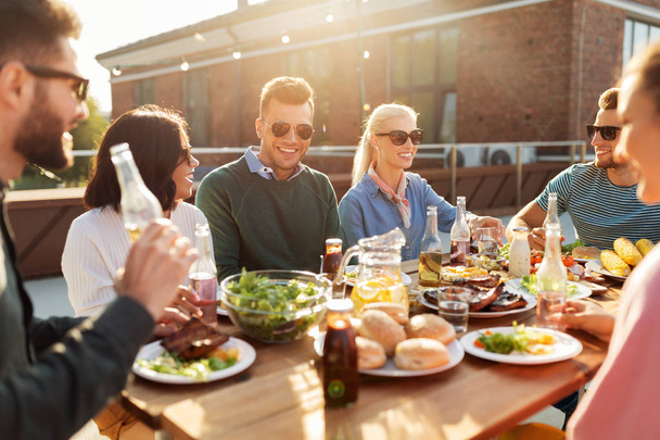 friends having dinner or bbq party on rooftop - Фото, изображение