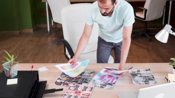 Pohledný mladý designér, který kontroluje jeho grafiky - Záběry, video