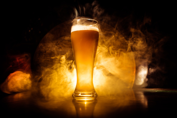 Concepto creativo. Vasos de cerveza sobre mesa de madera en fondo nebuloso tonificado oscuro
. - Foto, Imagen