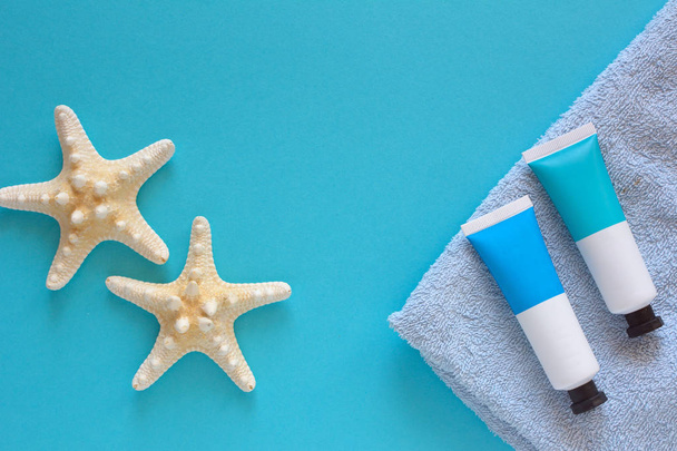 Concepto de vacaciones de verano con estrellas de mar y cosméticos en el fondo azul
. - Foto, Imagen