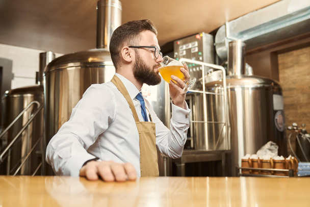 Bearded man in glasses tasting beer after brewing - Foto, Bild