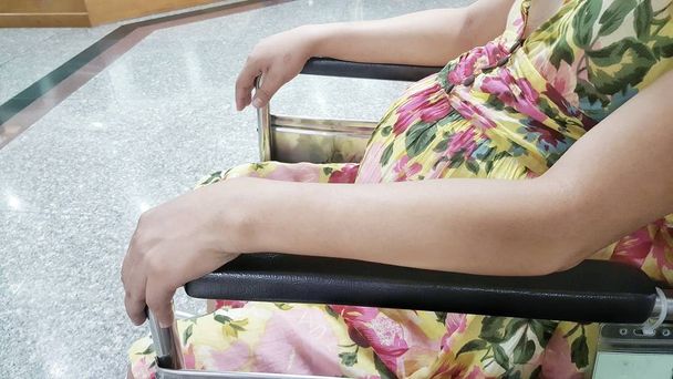 Беременная брюхо женщина сидит на стуле больницы для ожидания врача в больнице
. - Фото, изображение