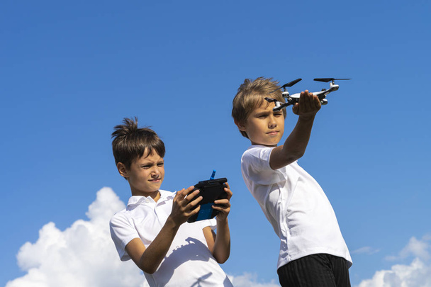 Boys playing with drone in summer day outdoors against blue sky - Foto, Imagem