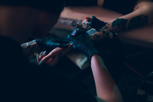 Tetovaný umělec si na paži dívky vytvoří tetování. - Fotografie, Obrázek