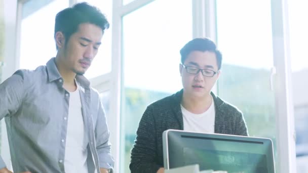 два молодих азіатських бізнесмени обговорюють бізнес в офісі, використовуючи настільний комп'ютер
 - Кадри, відео