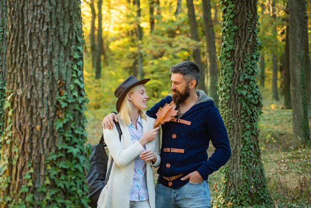 Pretty woman and handsome man walking in the Park and enjoying the beautiful autumn nature. Autumn outdoor portrait of beautiful happy girl and bearded man walking in park or forest. - Photo, image